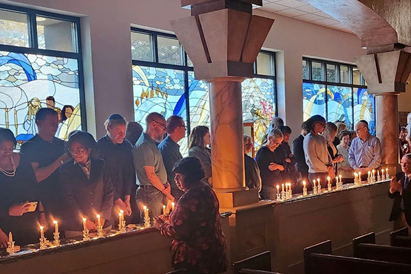 Several people standing in front of candles lighting them